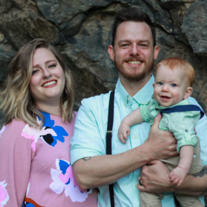couple and child posing in front of rocks